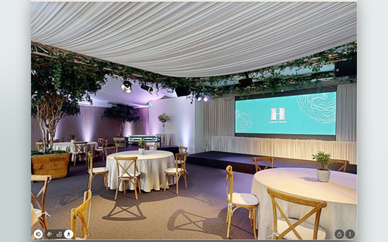 The Garden Pavilion set for dining, with round tables and a stage